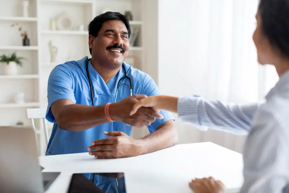 smiling indian doctor man uniform shaking hands with female patient